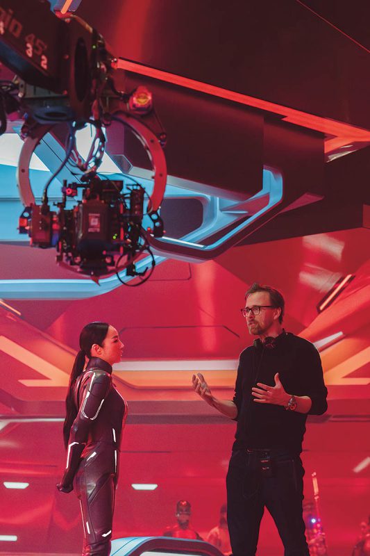 Joachim Rønning has a conversation with Greta Lee while surrounded by a massive and dramatic practical red set constructed for scenes that take place within the Dillinger Grid. (Photo: Leah Gallo)