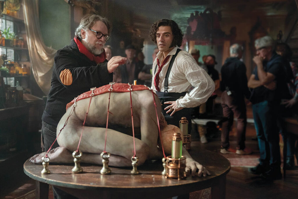 Guillermo del Toro discusses a scene with Oscar Isaac behind an anatomically detailed and realist rendition of a human body. (Photo: Ken Woroner)