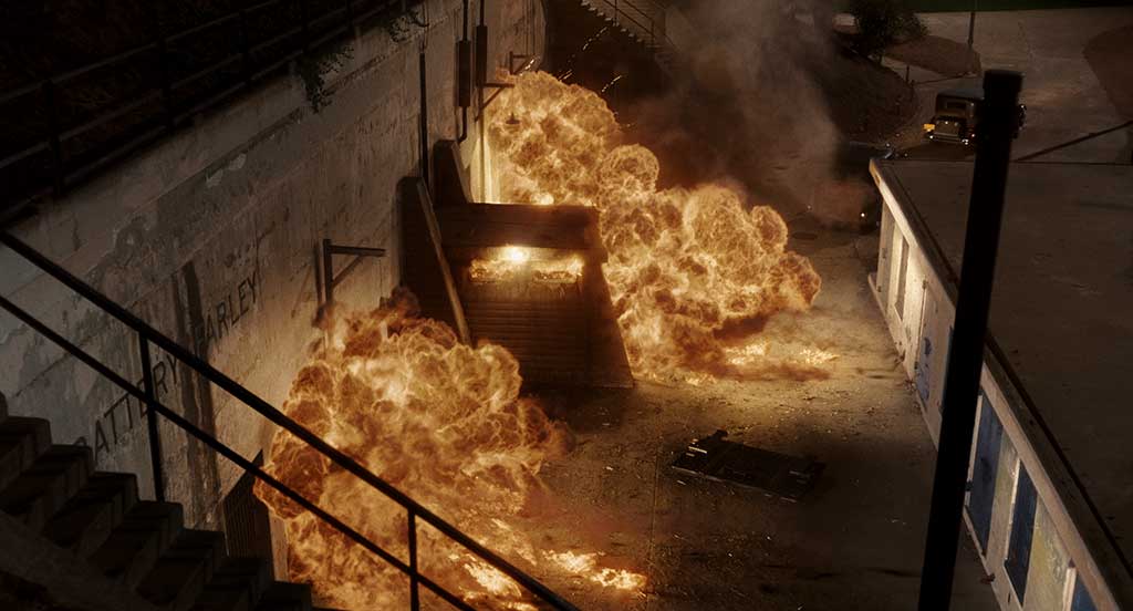 A massive explosion occurs, generating a lot of fire, smoke, embers and debris.